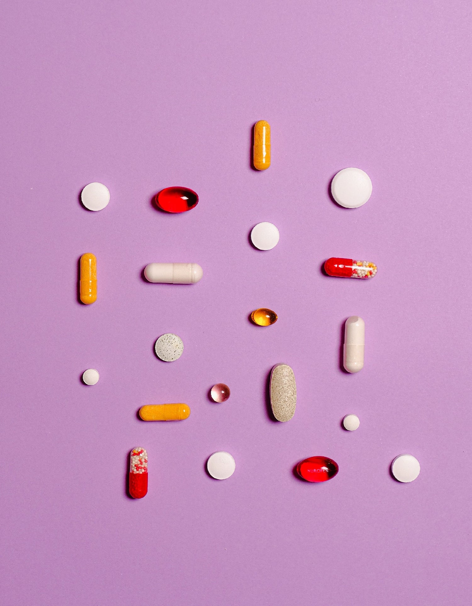 Hair loss vitamins against a purple background. Red, yellow, white, and beige pills for hair. Hair vitamins.